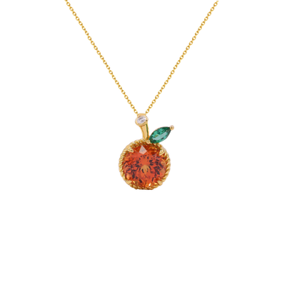 A gold necklace with an orange-shaped pendant featuring a faceted orange-red center, a small green marquise gemstone leaf, and a tiny clear accent stone on a white background.