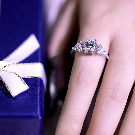 Diamond ring on a finger with a blurred jewelry box in the background